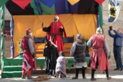 Een in het rood geklede acteur houdt een dramatische toespraak voor soldaten en publiek