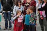 Een begeleidster richt zich tot de kinderen die op het versierde plein zitten