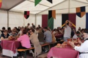 Abitanti e visitatori si fotografano durante il pranzo popolare sotto il tendone