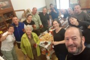 Abitanti e volontari posano con salumi e vino a una riunione