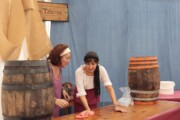 Due donne in costume puliscono un tavolo nella taverna del mercato