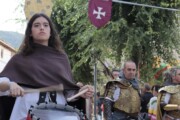 Una giovane suona il tamburo nella sfilata accanto a stendardi e cavalieri