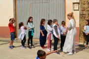 Bambini guardano una donna in costume spiegare un gioco tradizionale di legno