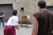Due figuranti mostrano un gioco popolare tradizionale a un gruppo di curiosi
