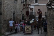 Un artista sui trampoli applaude accanto alla roulotte dei burattinai