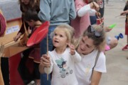 Una bambina bionda gioca con un piatto di legno al mercato