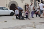 Bambini saltano sopra tegole di legno davanti al portale di pietra
