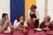 Una taverniera in costume distribuisce ciotole ai commensali del tendone