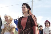 La regina Munia cammina accanto a una bambina con la cuffia bianca