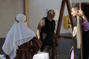 Accanto alla fucina una donna dal velo bianco attende il fabbro