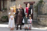 Una famiglia in costume posa davanti a una casa con il pozzo