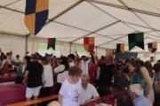 I commensali brindano con le brocche nell'atmosfera festiva del tendone