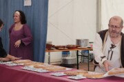 Due figuranti distribuiscono focacce dolci appena sfornate sotto il tendone medievale