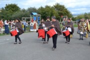 Tamburini sfilano suonando accanto all'area giochi per bambini