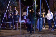 Un'artista esegue un'acrobazia aerea sospesa a un anello di notte