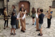 Bambini in tunica ballano in girotondo davanti a una porta antica