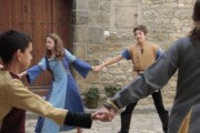 Bambini in costume medievale ballano in girotondo davanti a una porta antica