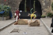Un'acrobata salta sopra le balle di paglia davanti a una porta di ferro