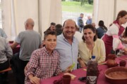 Una famiglia posa sorridente sotto il tendone del pranzo popolare