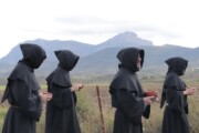 Quattro monaci in saio scuro contemplano il paesaggio montano vicino a Bailo