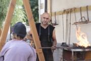Un artigiano fabbro lavora alla sua fucina durante il mercato medievale