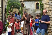 Un pellegrino con mantello bruno cammina sotto un arco del Cammino di Santiago