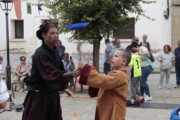 Un giocoliere si esibisce accanto a un bambino vestito da paggio