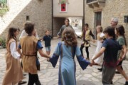 Alcuni bambini ballano in girotondo per una via selciata