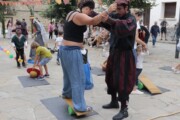Due artisti fanno un esercizio d'equilibrio su delle tavole in piazza