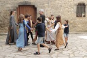 Alcuni bambini ballano in girotondo davanti a una facciata di pietra