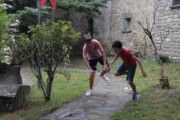 Due adolescenti giocano fra nastri tesi in un giardino