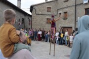 Un uomo sui trampoli saluta gli abitanti in piazza