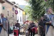 Una guardia di cavalieri sfila in corazze dorate per la via
