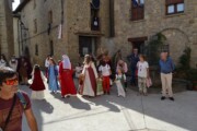 Alcuni figuranti attraversano la piazza con una fontana di pietra