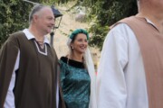 Tre figuranti conversano all'ombra vestiti in costume d'epoca