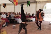 Un giullare fa la verticale davanti al pubblico durante il pranzo popolare
