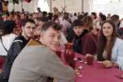 Alcuni giovani posano sorridenti alla tavola del pranzo popolare