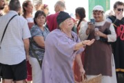 Una donna in costume da mendicante medievale chiede l'elemosina agli spettatori
