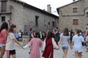 Bambine ballano in girotondo mentre un giullare suona il flauto