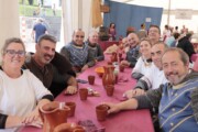 Commensali in abiti azzurri posano al pranzo popolare