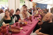 I commensali condividono brocche di birra locale sotto il tendone medievale