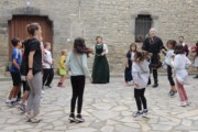 Bambini e adulti ballano in girotondo davanti alla chiesa