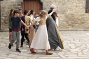 Bambini e un anziano ballano in girotondo davanti a una porta antica