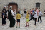 Bambini giocano al girotondo in una piazza porticata di pietra