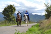 Due cavalieri in mantello cavalcano sulla via aragonese con il corteo