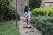 Una bambina salta tronchi di legno accanto ai muri del castello