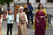 Un gruppo posa in piazza accanto a un arazzo di Bailo