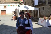 Due donne in costume posano accanto al tendone del mercato medievale