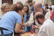 Un artigiano lavora all'incudine davanti a bambine e giovani nel recinto