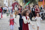 Bambini in costume agitano bandierine nella sfilata per la via